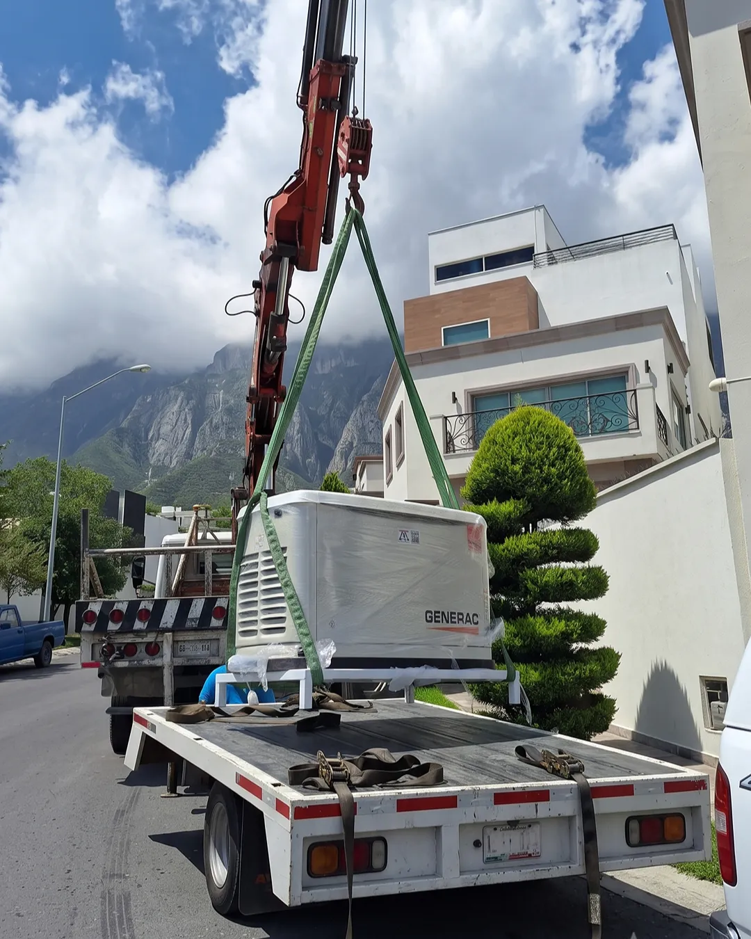 Grúa bajando un generador Generac de la caja de un camión frente a una casa en Monterrey